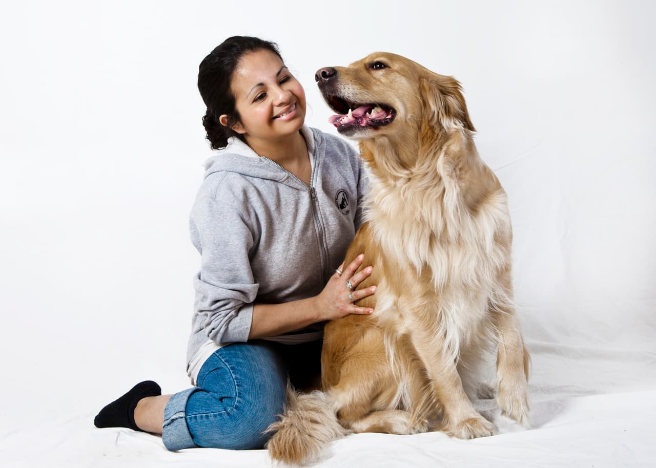 Nanna sidder på gulvet med armen om en golden retriever